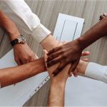 A group of people coming together with their hands clasped in a show of teamwork.