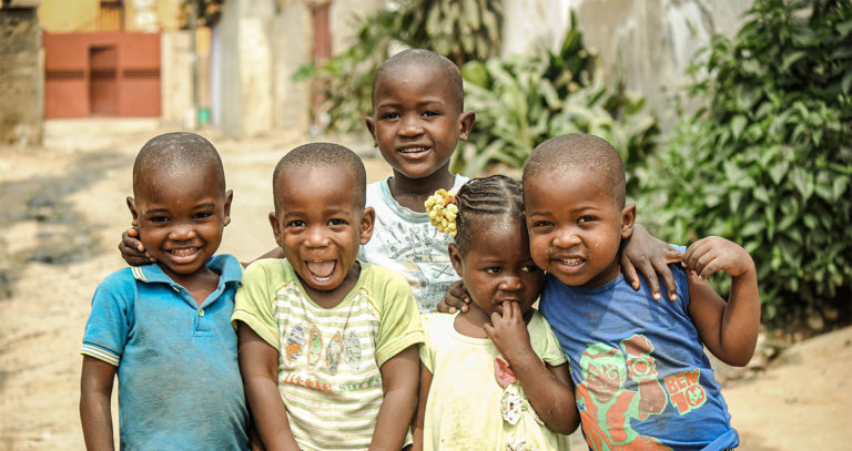 Several youngsters, wearing bright smiles, stand together and pose happily for a photograph.