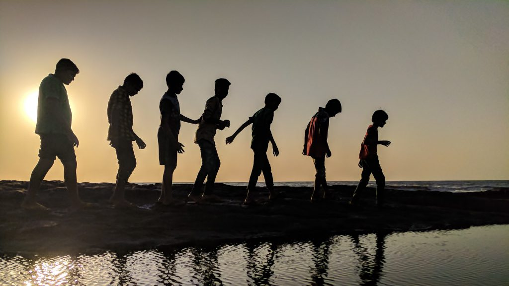 Silhouettes of individuals strolling along the shoreline during a picturesque sunset on the beach